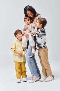 Asya kökenli bir grup çocuk, gri bir arka plana karşı bir stüdyoda birlik ve çeşitlilik sergilemek için bir arada duruyorlar..