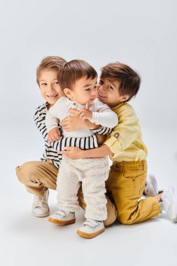 Bir grup genç, gri bir arkaplana karşı stüdyoda birlikte oturuyorlar..