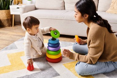 A young Asian mother happily interacts with her little son on the floor of their cozy living room, creating fun memories together. clipart