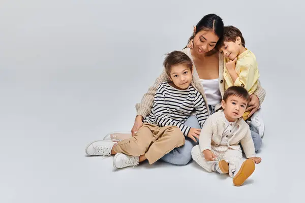 Genç Bir Asyalı Anne Çocuklarıyla Birlikte Gri Bir Zeminde Sakin — Stok fotoğraf