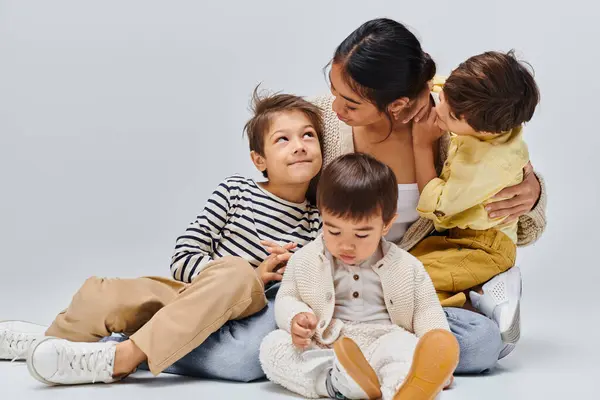 Asian Mother Sits Floor Her Children Sharing Loving Embrace Studio — Stock Photo, Image