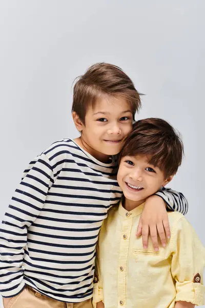 stock image Two young boys, one standing confidently and the other with a playful smile, pose for a portrait in a studio setting.