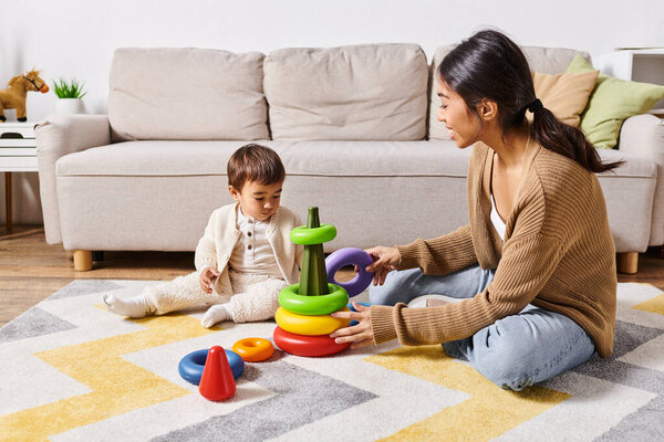 A young Asian mother joyfully interacts with her little son, playing together on the floor in their homes living room.