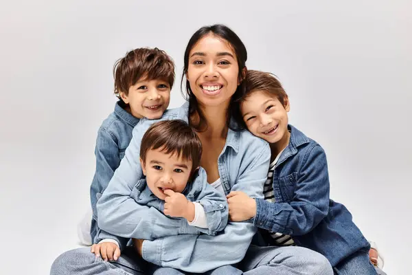 Stock image A young Asian mother in denim clothes sits on the floor with her little sons, creating a scene of familial bonds.