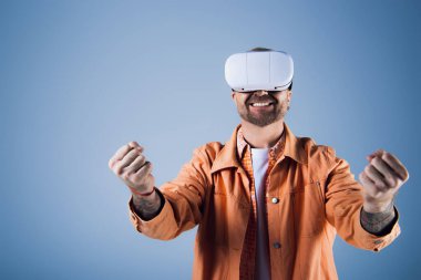 A man in an orange shirt and tie explores the virtual world with a VR headset in a studio setting. clipart