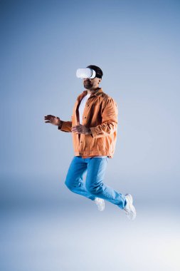 A man with a hat jumps in the air within a studio setting while wearing a VR headset for metaverse exploration. clipart