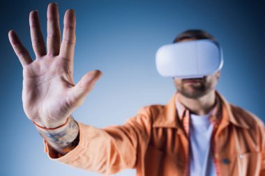 Stüdyo ortamındaki bir adam, Metaverse 'in dijital dünyasına dalmış bir kulaklıkla sanal gerçekliği deneyimliyor..