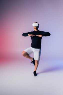 Siyah tişörtlü ve beyaz şortlu bir adam dinamik bir dans hareketi yapıyor. Stüdyo ortamında beceri ve tutku gösteriyor..