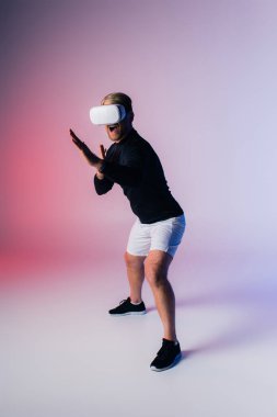 Siyah tişörtlü ve beyaz şortlu bir adam stüdyo ortamında güven içinde poz veriyor ve VR 'da çarpıcı bir kontrast oluşturuyor.
