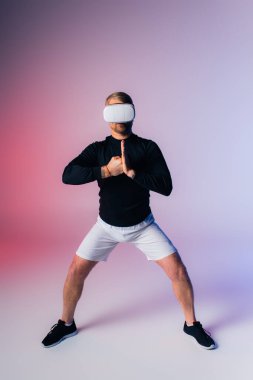 VR giyen bir adam pembe ve mavi bir arka planın önünde durur, hayal gücü ve hayallerin dünyasında kaybolur..