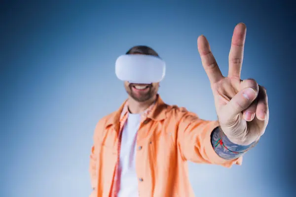 一个穿着橙色衬衫 头戴眼罩的男人在工作室里 通过虚拟现实探索现实世界的边界 — 图库照片