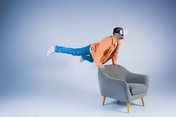 Man Orange Shirt Executes Mesmerizing Trick Chair Studio Setting Showcasing — Stock Photo, Image