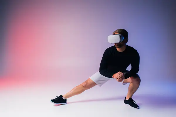 A man in a black shirt and white shorts delves into virtual reality while wearing a headset in a studio setting.