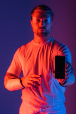 Akıllı gözlüklü bir adam cep telefonunu tutuyor, bir stüdyo ortamında Metaverse 'in sanal gerçekliğine dalmış..