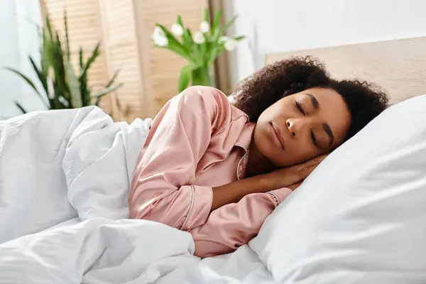 A curly African American woman in pajamas lays in bed, her head resting on the pillow, surrounded by a tranquil morning scene.