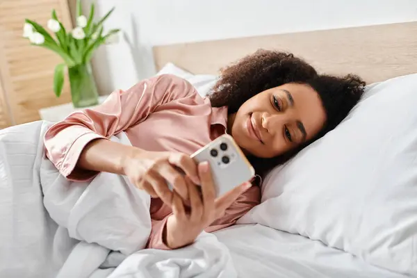 Curly African American Woman Pajamas Laying Bed Holding Cell Phone — Stock Photo, Image