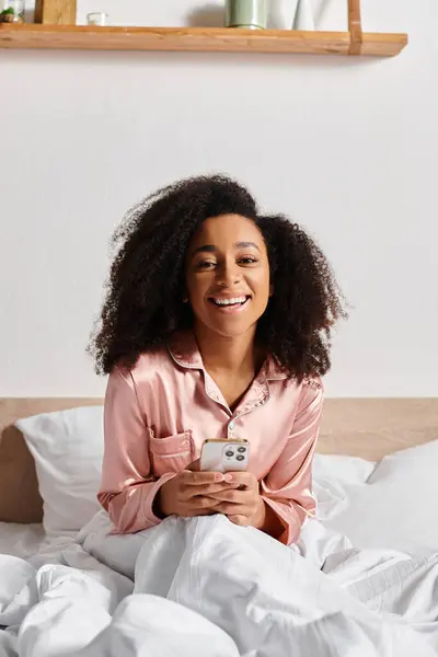 Lockig Afroamerikansk Kvinna Pyjamas Sittandes Sängen Uppslukad Sin Mobilskärm Morgonen — Stockfoto
