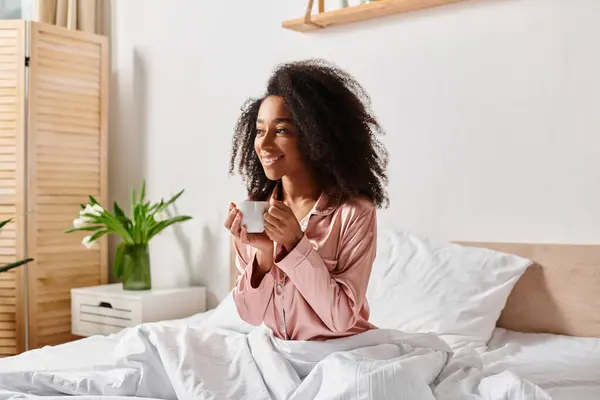 Curly African American Woman Pajamas Sitting Bed Enjoying Cup Coffee — Stockfoto