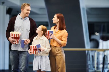 Mutlu bir aile, elinde patlamış mısır dolu bir kutu tutarak bir çember oluşturur. Birlikte eğlenceli bir film gecesinin tadını çıkarırlar..