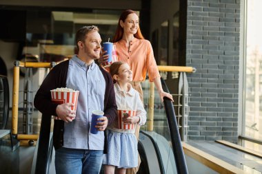 Bir adam ve ailesi mutlu bir şekilde yürüyen merdivende yürürler, sinemada ailecek vakit geçirirler..