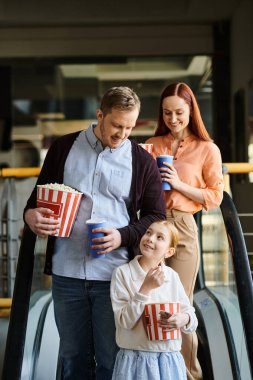 A man and a little girl happily stand on an escalator in a cinema, enjoying family time together. clipart