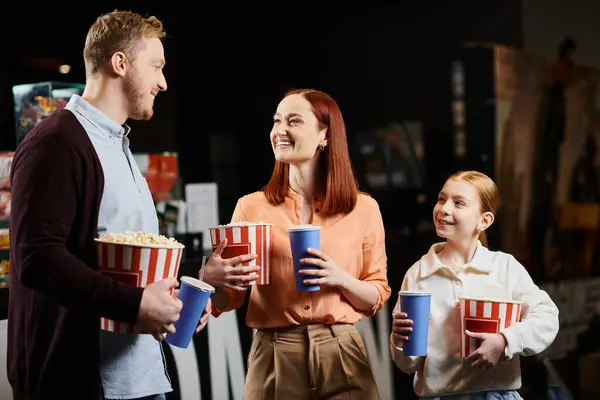 ポップコーンのカップを持って 映画館で喜びの瞬間を共有する男と雇用家族が一緒に立っています — ストック写真