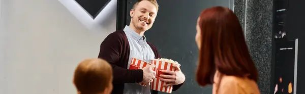 在一家电影院里 男人在一个女人面前高高兴兴地拿着一盒爆米花 两个人都笑得很开心 — 图库照片