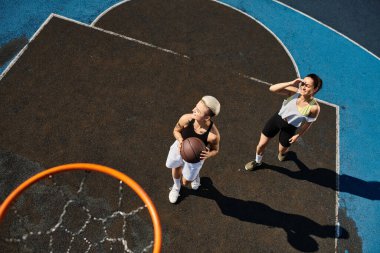 Kadınlar sahada enerjik bir şekilde basketbol oynuyor, atletizm ve takım çalışmalarını yaz güneşinin altında sergiliyorlar..