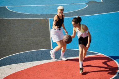 İki genç kadın, bir basketbol sahasının tepesinde kararlı ve becerikli bir şekilde maça çıkmaya hazırlar..