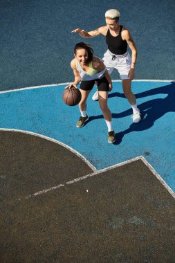 Bir kadın sahada enerjik bir şekilde basketbol oynuyor, atletizm ve takım çalışmalarını bir yaz oyununda sergiliyor..