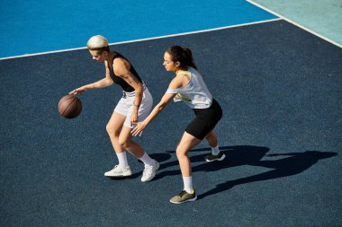 Atletik genç kadınlar güneşli bir günde, bir basketbol sahasında zaferle ayakta duruyor, dayanıklılık ve takım çalışmasının vücut bulmuş hali..