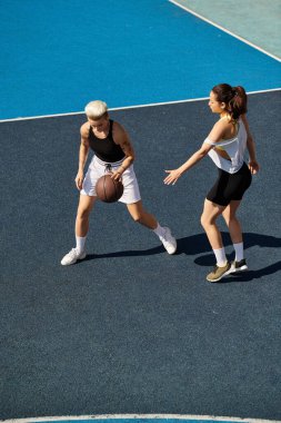 Güneşli bir günde dışarıda basketbol oynayan atletik genç kadınlar yeteneklerini ve takım çalışmalarını sergiliyorlar..