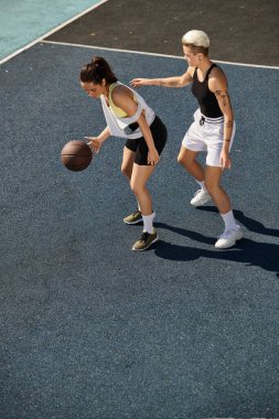 Two athletic women standing confidently on a basketball court. clipart