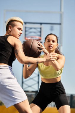 Güneşli bir günde dışarıda basketbol oynayan kadınlar atletizm ve takım çalışmalarını sergiliyorlar..