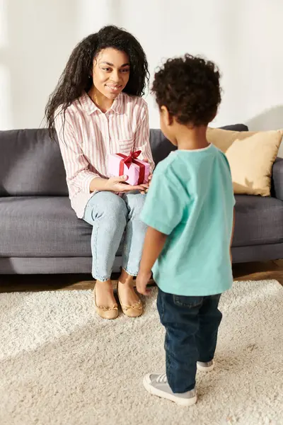 stock image cheerful african american woman sitting and holding present from her little son, Mothers day