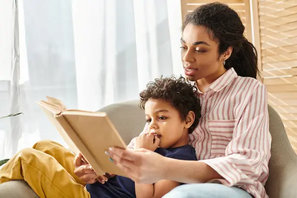 stock image cheerful african american woman in cozy attire reading book with her little cute son at home