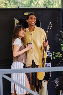 Bir adam açık hava ortamında bir kadının yanında dururken bir gitar tutar. Müzik ve aşkın ahenkli bir anını yaratır..