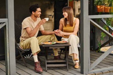 A man and a woman sit on a porch, enjoying a delicious meal together. clipart