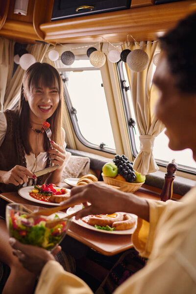 Разнообразная группа друзей, наслаждающихся общей едой и беседой за столом, наполненным едой.