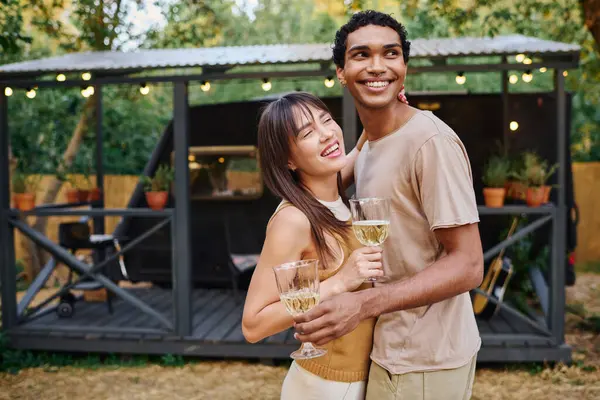 stock image A man and a woman clink wine glasses, enjoying a romantic moment in a cozy camper van.