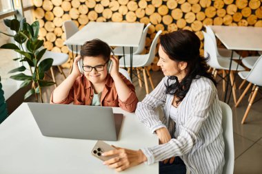 Neşeli anne, Down sendromlu oğluyla, o laptopla oynarken kafede vakit geçiriyor.