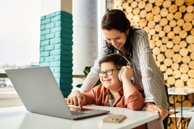 Neşeli anne, Down sendromlu oğluyla, o laptopla oynarken kafede vakit geçiriyor.