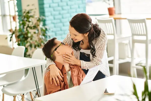 stock image positive good looking mother in cozy clothes with her inclusive son with Down syndrome in cafe