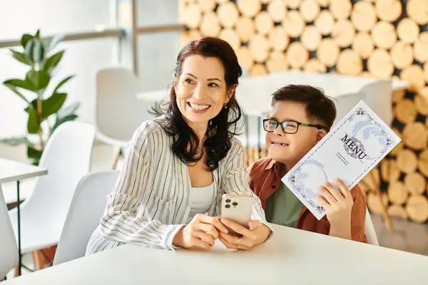 merry good looking woman in everyday clothes with her inclusive son with Down syndrome holding menu
