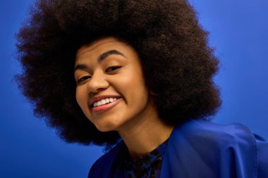 Close-up of stylish African American woman with impressive afro hair, posing against vibrant backdrop. clipart