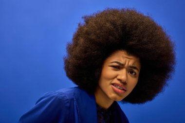 Hareketli bir arka planda etkileyici bir afro saçı olan şık bir Afro-Amerikan kadının yakın çekimi..