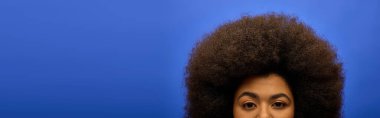 Stylish African American woman in trendy attire making a funny face with her afro hair. clipart