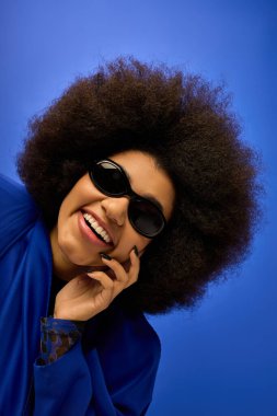 Modayı takip eden Afro-Amerikan bir kadın canlı bir arka plana karşı şık bir şekilde poz veriyor..