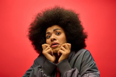 Moda giysileri içinde şık bir Afro-Amerikan kadın, şaşırmış bir ifade sergiliyor..