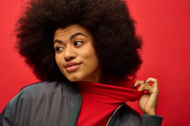Ensesinde çarpıcı kırmızı bir eşarpla şık bir Afro-Amerikan kadın moda giysileri sergiliyor..